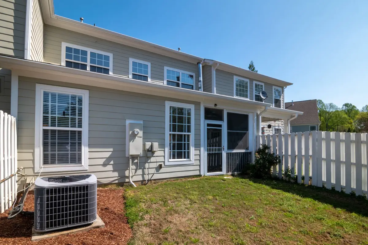 Two-story home with gray lap siding, white windows and a white picket fence in the backyard