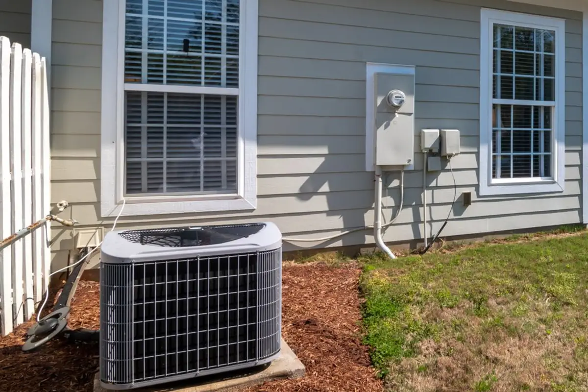 Outdoor air-conditioning condenser beside a home with gray siding