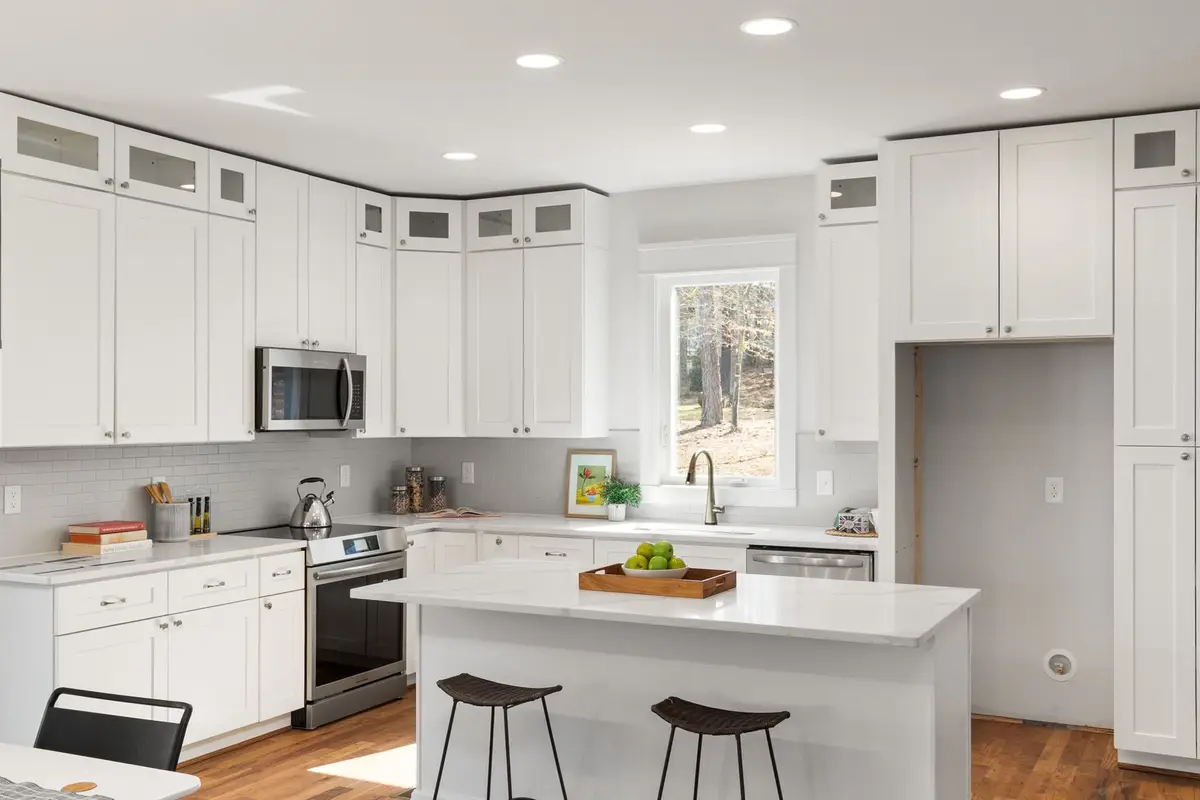 Bright remodeled kitchen with white cabinets, a center island and stainless appliances